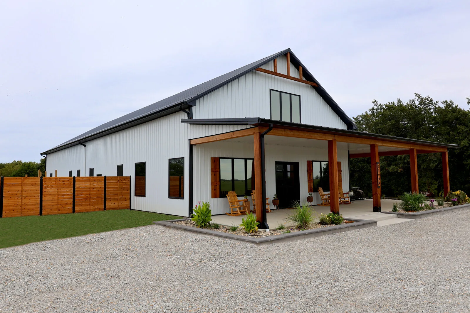 White modern farmhouse barndominium with timber porch